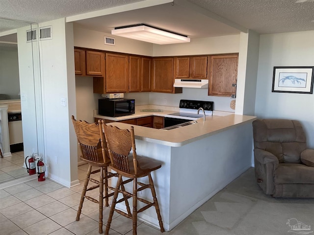 kitchen with kitchen peninsula, range with electric cooktop, a breakfast bar, and a textured ceiling