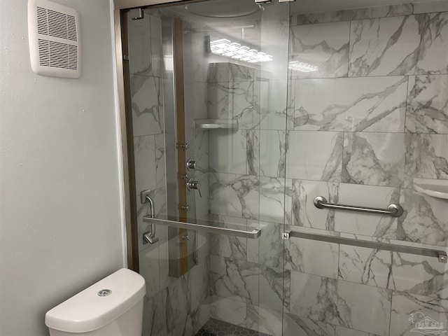 bathroom featuring a shower with door and toilet