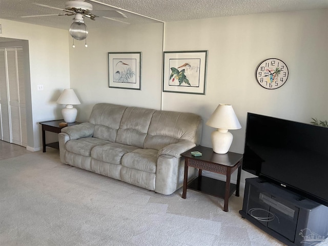 living room featuring ceiling fan, light colored carpet, and a textured ceiling