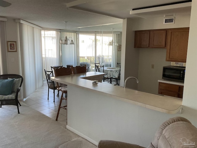 kitchen with decorative light fixtures, light tile patterned floors, a breakfast bar, and a wealth of natural light