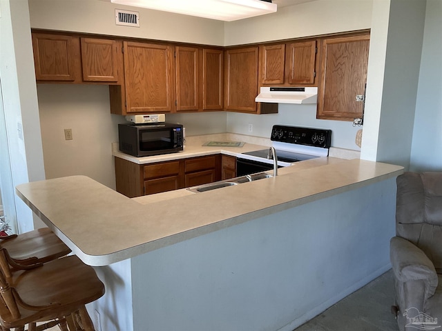 kitchen featuring a kitchen breakfast bar, kitchen peninsula, sink, and white electric range oven