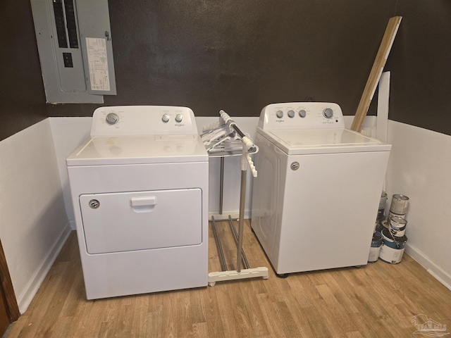 clothes washing area featuring washing machine and dryer, electric panel, and light hardwood / wood-style flooring