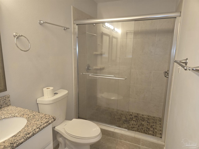 bathroom with tile patterned flooring, vanity, an enclosed shower, and toilet