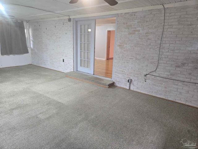 unfurnished room with ceiling fan, carpet, and brick wall