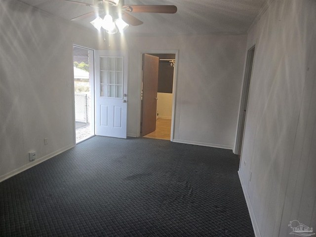 spare room featuring ceiling fan and dark colored carpet