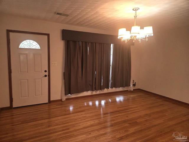 foyer entrance featuring hardwood / wood-style floors and an inviting chandelier