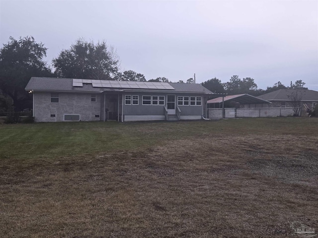 rear view of house with solar panels and a lawn