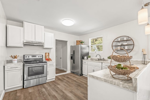 kitchen featuring stainless steel appliances, sink, decorative light fixtures, white cabinets, and light hardwood / wood-style floors