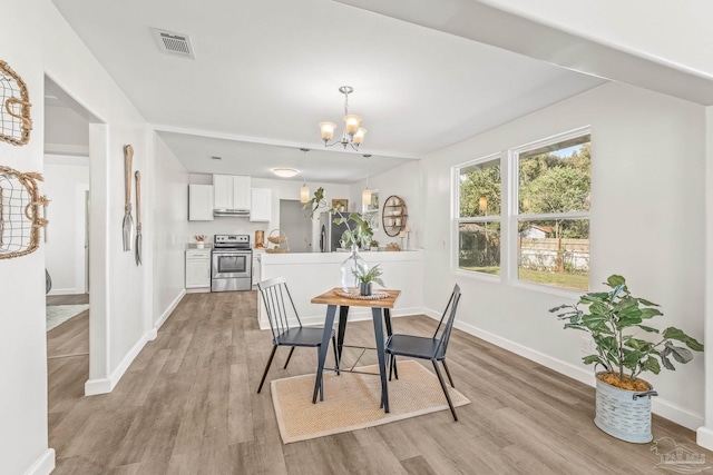 dining room with light hardwood / wood-style flooring and a notable chandelier