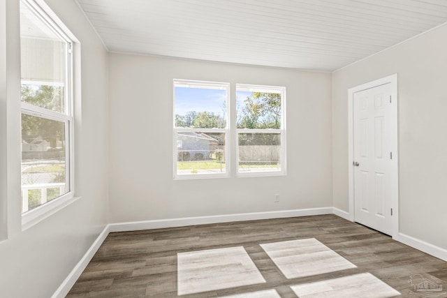 unfurnished room featuring dark hardwood / wood-style floors, a healthy amount of sunlight, and wood ceiling