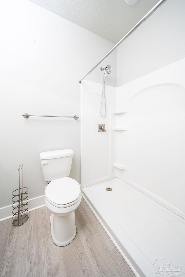 bathroom featuring hardwood / wood-style floors, toilet, and a shower