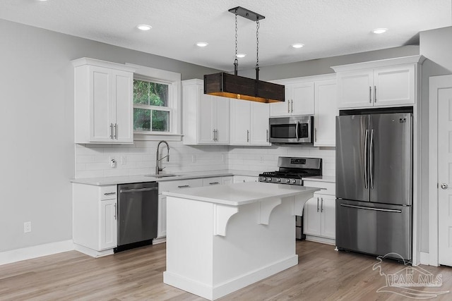 kitchen with a kitchen island, white cabinets, decorative light fixtures, and stainless steel appliances