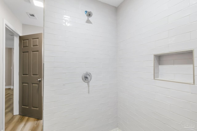 bathroom featuring hardwood / wood-style flooring and tiled shower