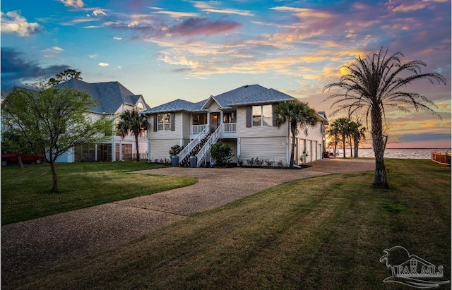 view of front of house featuring stairway, a lawn, and driveway