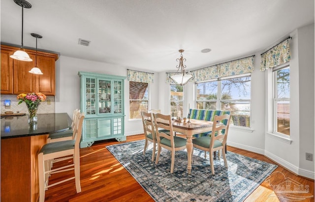 dining area featuring visible vents, baseboards, and wood finished floors