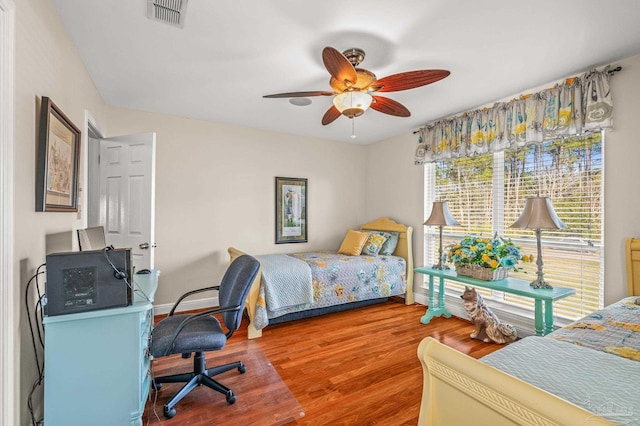 bedroom featuring visible vents, baseboards, wood finished floors, and a ceiling fan