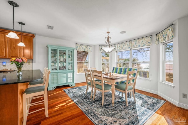 dining area with visible vents, baseboards, and dark wood-style floors