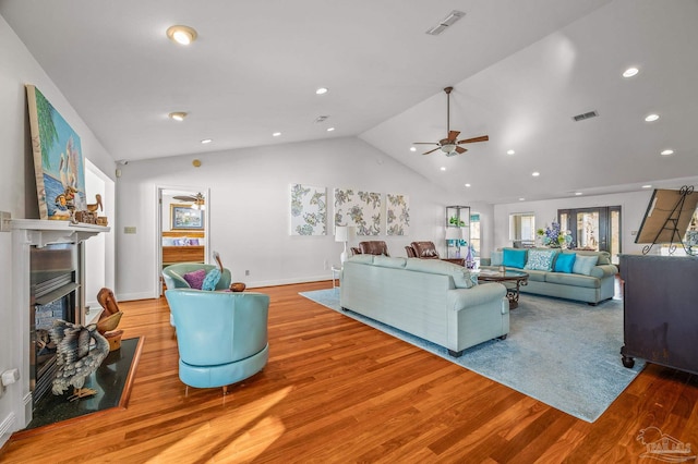 living area featuring visible vents, a fireplace, lofted ceiling, and wood finished floors