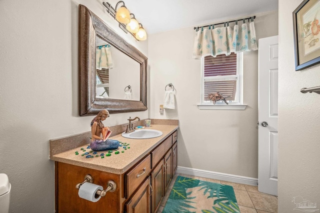 bathroom with baseboards, toilet, vanity, and tile patterned flooring