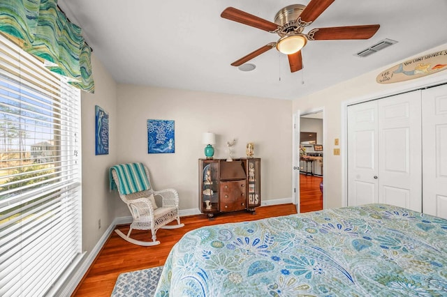 bedroom featuring a ceiling fan, wood finished floors, visible vents, baseboards, and a closet