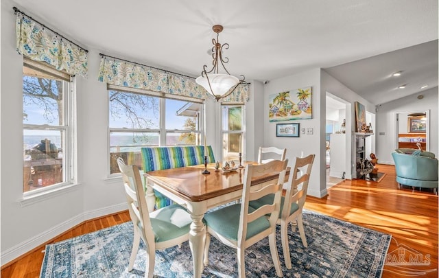 dining room featuring baseboards, wood finished floors, and vaulted ceiling