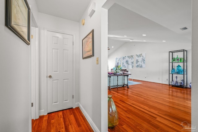 hallway with visible vents, baseboards, lofted ceiling, recessed lighting, and wood finished floors