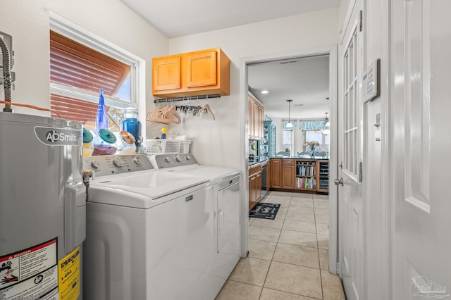 washroom featuring light tile patterned floors, laundry area, water heater, and washing machine and clothes dryer