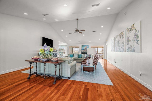 living area featuring visible vents, high vaulted ceiling, baseboards, and wood finished floors