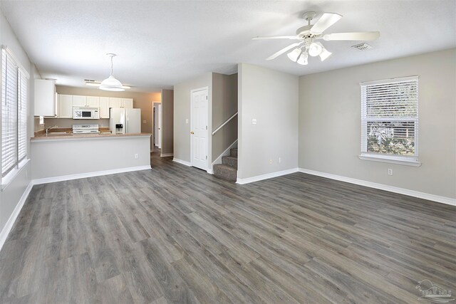 unfurnished living room featuring dark hardwood / wood-style floors, ceiling fan, a healthy amount of sunlight, and sink