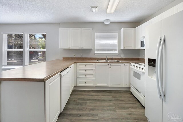 kitchen featuring kitchen peninsula, dark hardwood / wood-style flooring, white appliances, sink, and white cabinets