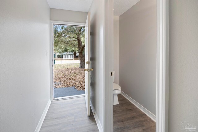 doorway with a textured ceiling and light hardwood / wood-style floors