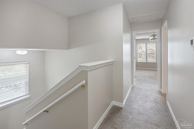 corridor featuring a textured ceiling and light colored carpet