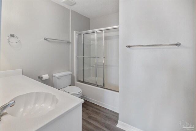 full bathroom featuring enclosed tub / shower combo, wood-type flooring, a textured ceiling, toilet, and vanity