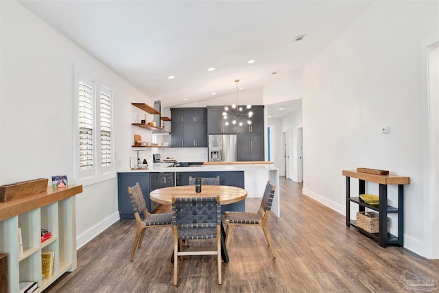 dining room with dark hardwood / wood-style flooring, a chandelier, and vaulted ceiling