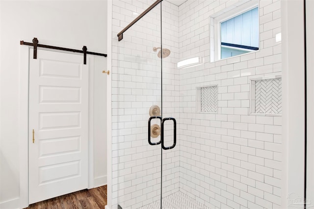 bathroom with a shower with shower door and wood-type flooring