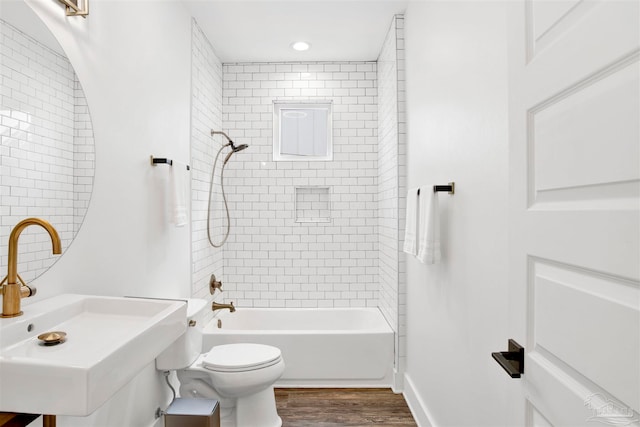 full bathroom featuring sink, toilet, wood-type flooring, and tiled shower / bath