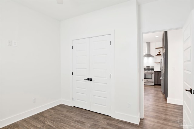 unfurnished bedroom with dark wood-type flooring, stainless steel refrigerator, and a closet