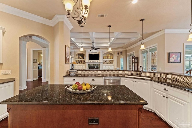 kitchen with dark stone counters, beamed ceiling, pendant lighting, sink, and coffered ceiling