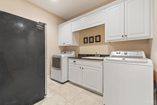 clothes washing area featuring light tile patterned flooring, cabinets, sink, and washer and clothes dryer