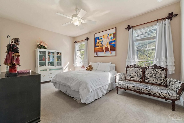 carpeted bedroom featuring multiple windows and ceiling fan