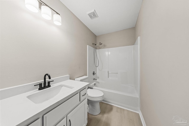 full bathroom featuring a textured ceiling, toilet,  shower combination, vanity, and hardwood / wood-style flooring