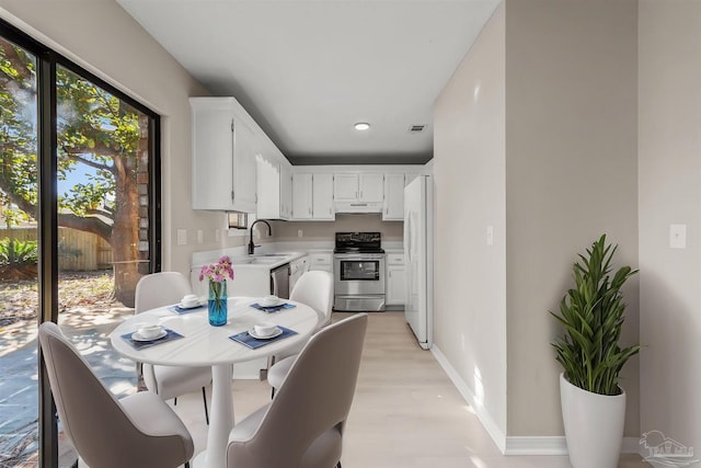 kitchen with appliances with stainless steel finishes, light hardwood / wood-style floors, white cabinetry, and sink