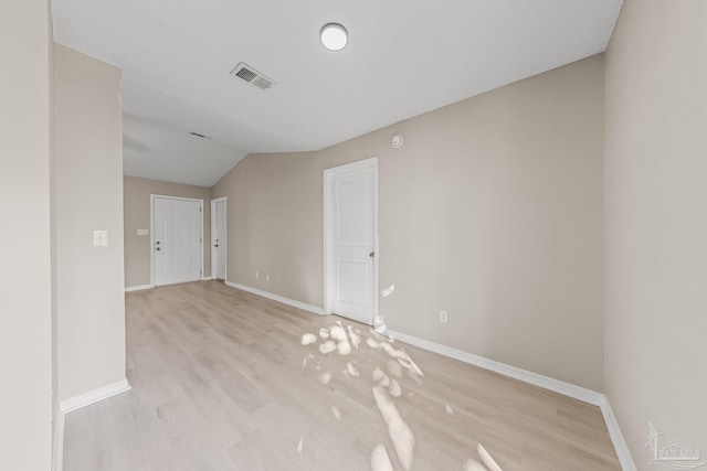 spare room featuring vaulted ceiling and light hardwood / wood-style flooring