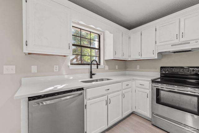 kitchen with light wood-type flooring, a textured ceiling, stainless steel appliances, sink, and white cabinetry