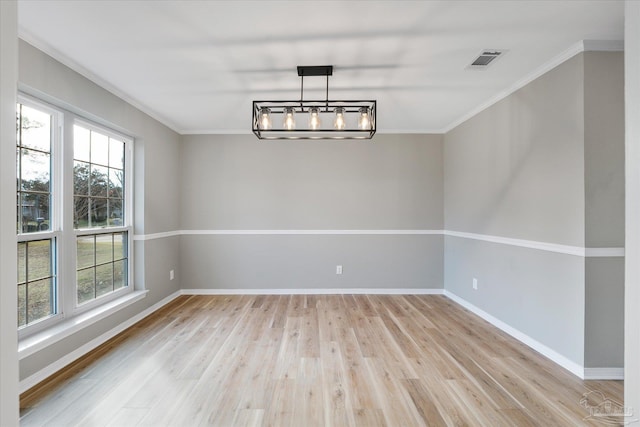 unfurnished room featuring an inviting chandelier, crown molding, and light hardwood / wood-style flooring