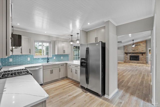 kitchen with tasteful backsplash, a fireplace, sink, light stone countertops, and stainless steel appliances