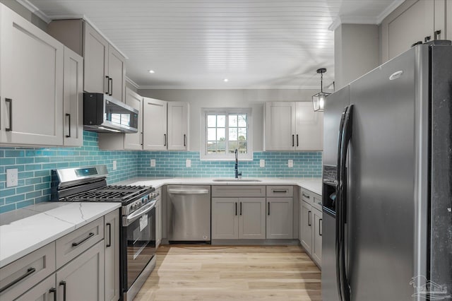 kitchen with appliances with stainless steel finishes, gray cabinetry, decorative light fixtures, light wood-type flooring, and sink