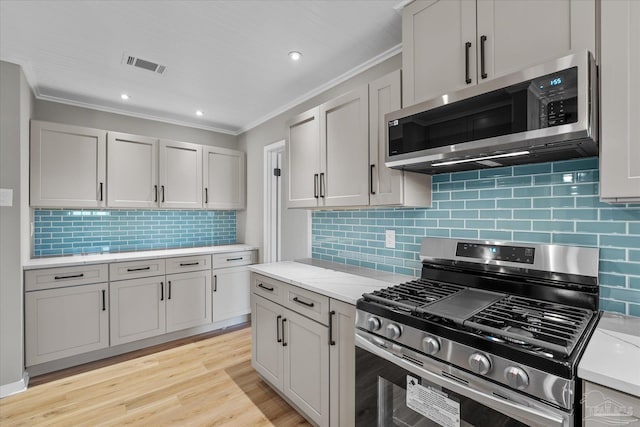 kitchen featuring stainless steel appliances, backsplash, ornamental molding, light wood-type flooring, and light stone counters