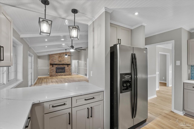 kitchen featuring light stone countertops, stainless steel refrigerator with ice dispenser, decorative light fixtures, a fireplace, and ceiling fan