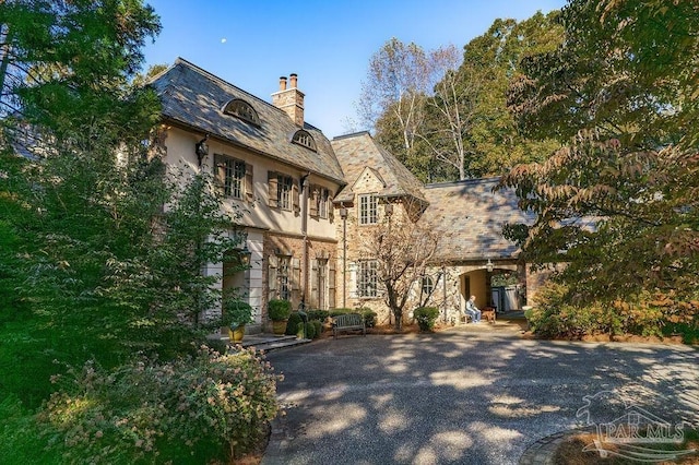 view of front of property with a high end roof, stone siding, and a chimney